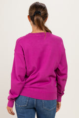 woman wearing a bright pink maternity sweater viewed from the back with long sleeves and a relaxed fit