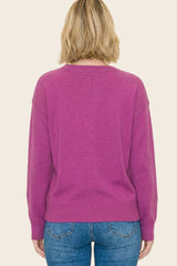woman wearing a back view of a magenta oversized sweater paired with blue jeans