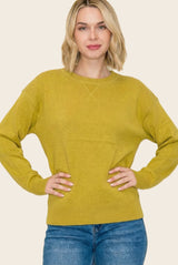 woman wearing a mustard yellow long sleeve sweater with a relaxed fit and crew neckline, paired with blue jeans