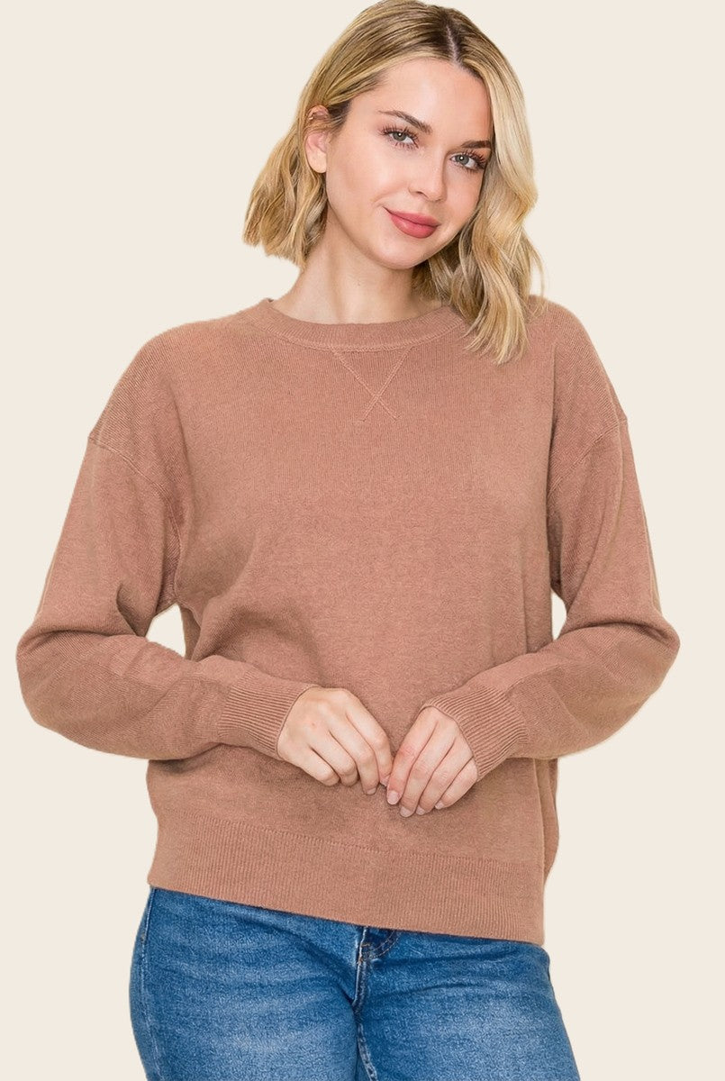 woman wearing a beige oversized sweater with a crew neckline and long sleeves, paired with blue jeans