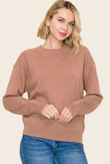 woman wearing a beige oversized sweater with a crew neckline and long sleeves, paired with blue jeans