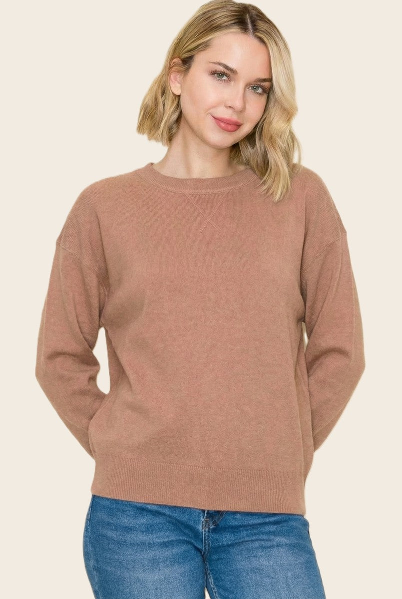 woman wearing a light brown cozy sweater with a round neckline and relaxed fit, paired with blue jeans