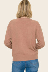 woman wearing a cozy tan sweater with a relaxed fit and long sleeves, paired with blue jeans, viewed from the back