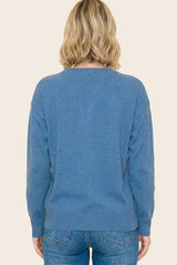 woman wearing a soft blue sweater with a relaxed fit and ribbed hem, viewed from the back