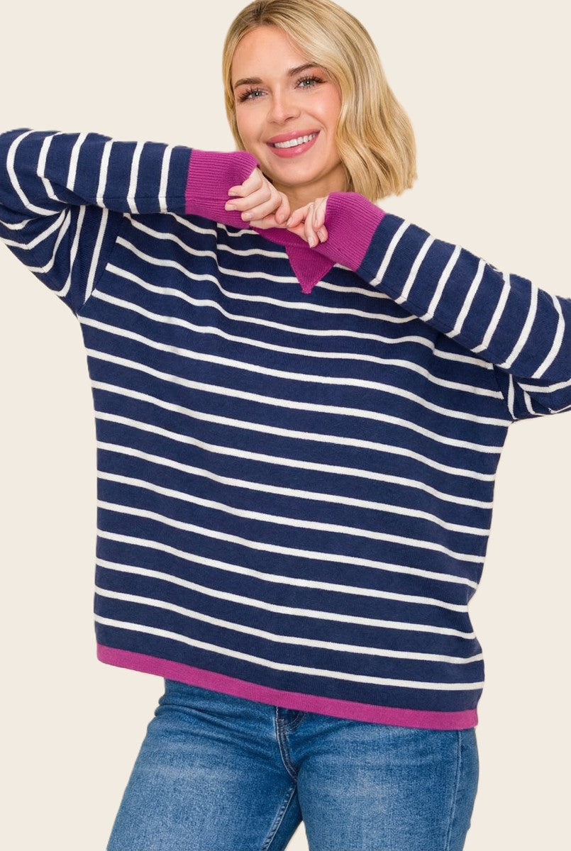 woman wearing a navy and white striped oversized sweater with pink accents and smiling