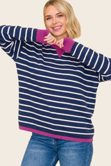 woman wearing a navy and white striped oversized sweater with pink accents and smiling