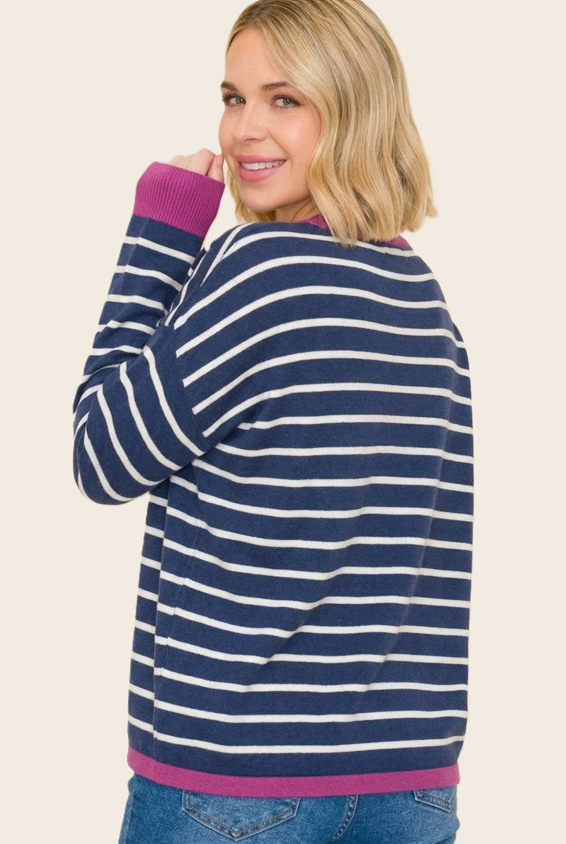 woman wearing a navy blue and white striped long sleeve sweater with purple accents, smiling and facing away from the camera