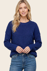woman wearing a navy blue textured knit sweater with a relaxed fit and long sleeves, paired with light blue jeans