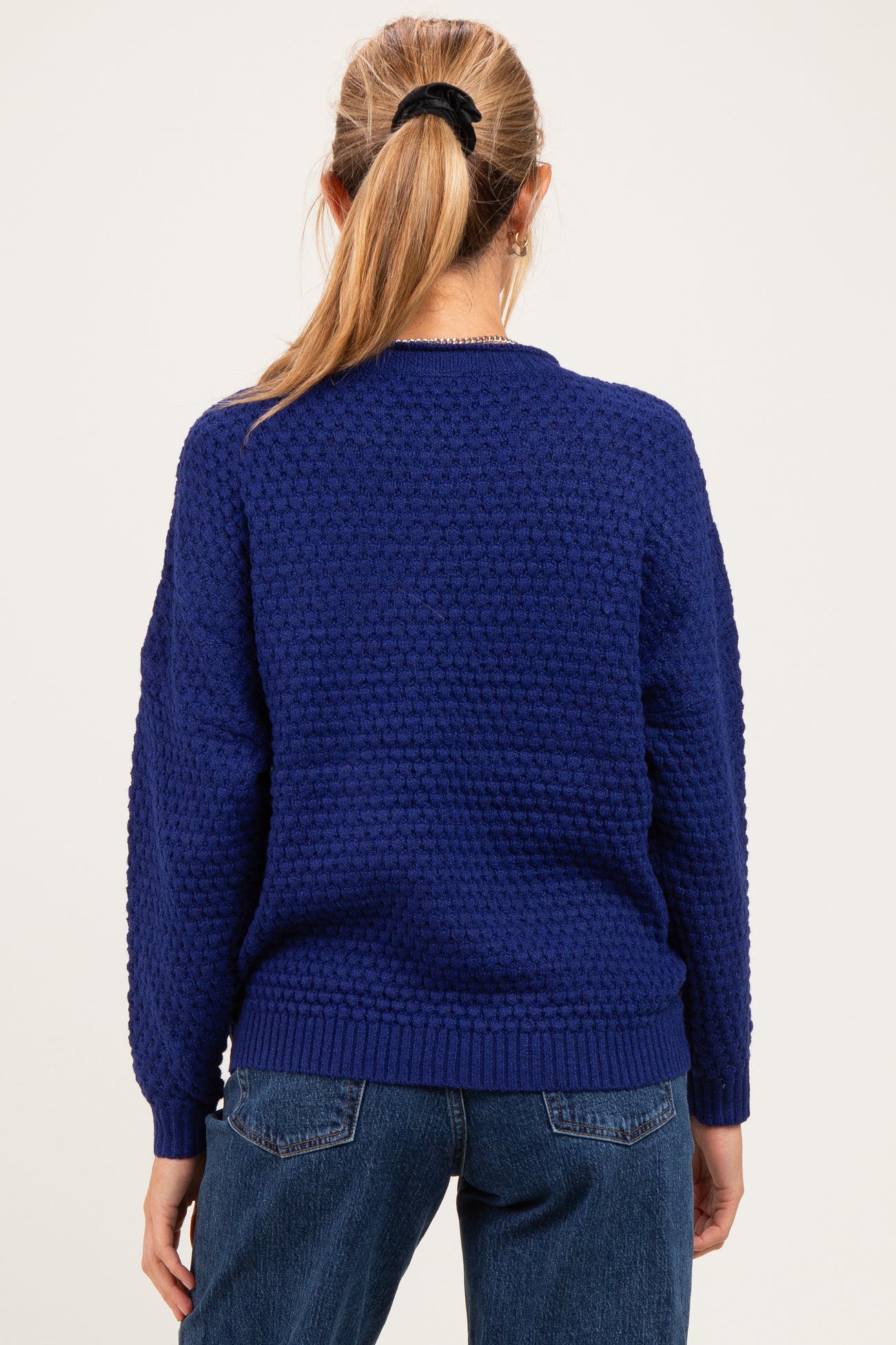 woman wearing a navy blue maternity sweater with textured pattern and a relaxed fit, back view