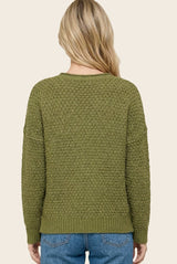 woman wearing an olive green textured knit sweater with a relaxed fit, viewed from the back