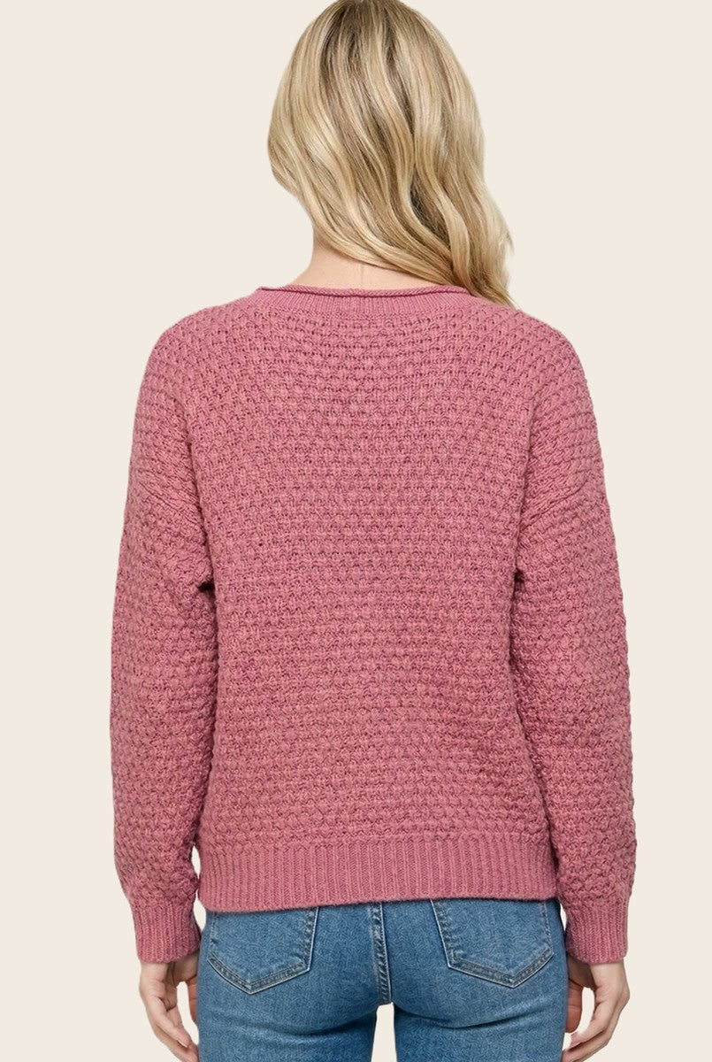 woman wearing a relaxed fit dusty pink textured sweater with a round neckline and ribbed cuffs, seen from the back