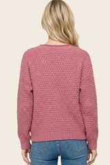 woman wearing a relaxed fit dusty pink textured sweater with a round neckline and ribbed cuffs, seen from the back