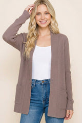 woman wearing a taupe ribbed cardigan with front pockets over a white tank top and blue jeans