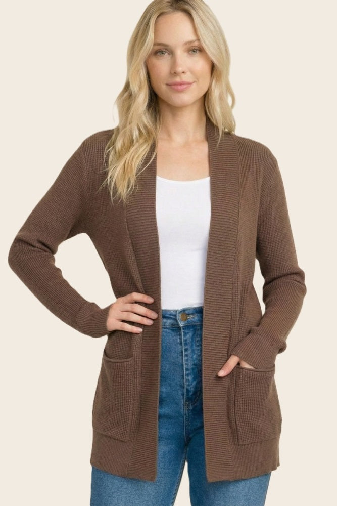 woman wearing a brown ribbed cardigan with pockets over a white top and high-waisted jeans