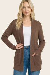 woman wearing a brown ribbed cardigan with pockets over a white top and high-waisted jeans