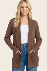 woman wearing a brown ribbed cardigan with pockets and a white tank top, styled with blue high-waisted jeans