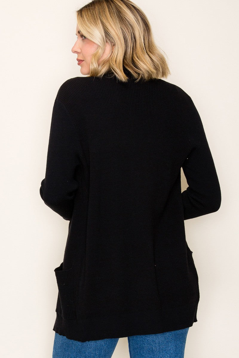 woman wearing a black long cardigan with side pockets, shown from the back