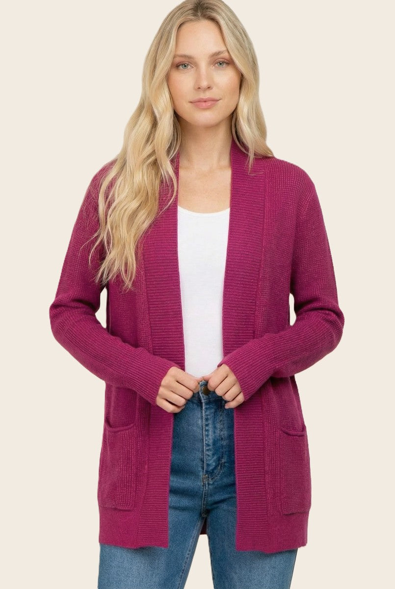 woman wearing a fuchsia long sleeve cardigan with pockets and a white top paired with blue jeans