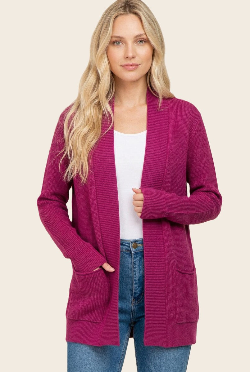woman wearing a vibrant fuchsia cardigan with pockets over a white top and blue jeans