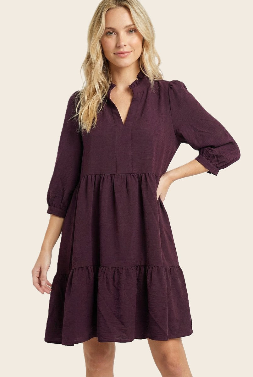 woman wearing a deep purple short sleeve tiered dress with a v-neck and ruffle details
