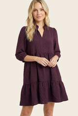 woman wearing a dark purple tiered dress with a v-neck and three-quarter sleeves