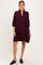woman wearing a dark burgundy maternity dress with puff sleeves and a tiered hem, styled with black mules