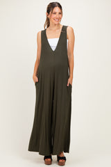 woman wearing an olive green maternity jumpsuit with a deep v-neck and pockets, showing her baby bump