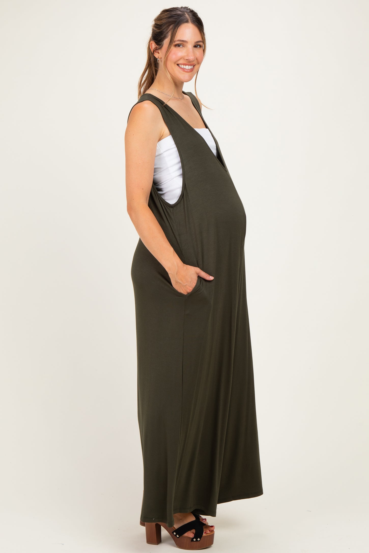 woman wearing an olive green sleeveless maternity dress with pockets and a visible baby bump