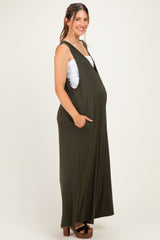 woman wearing an olive green sleeveless maternity dress with pockets and a visible baby bump