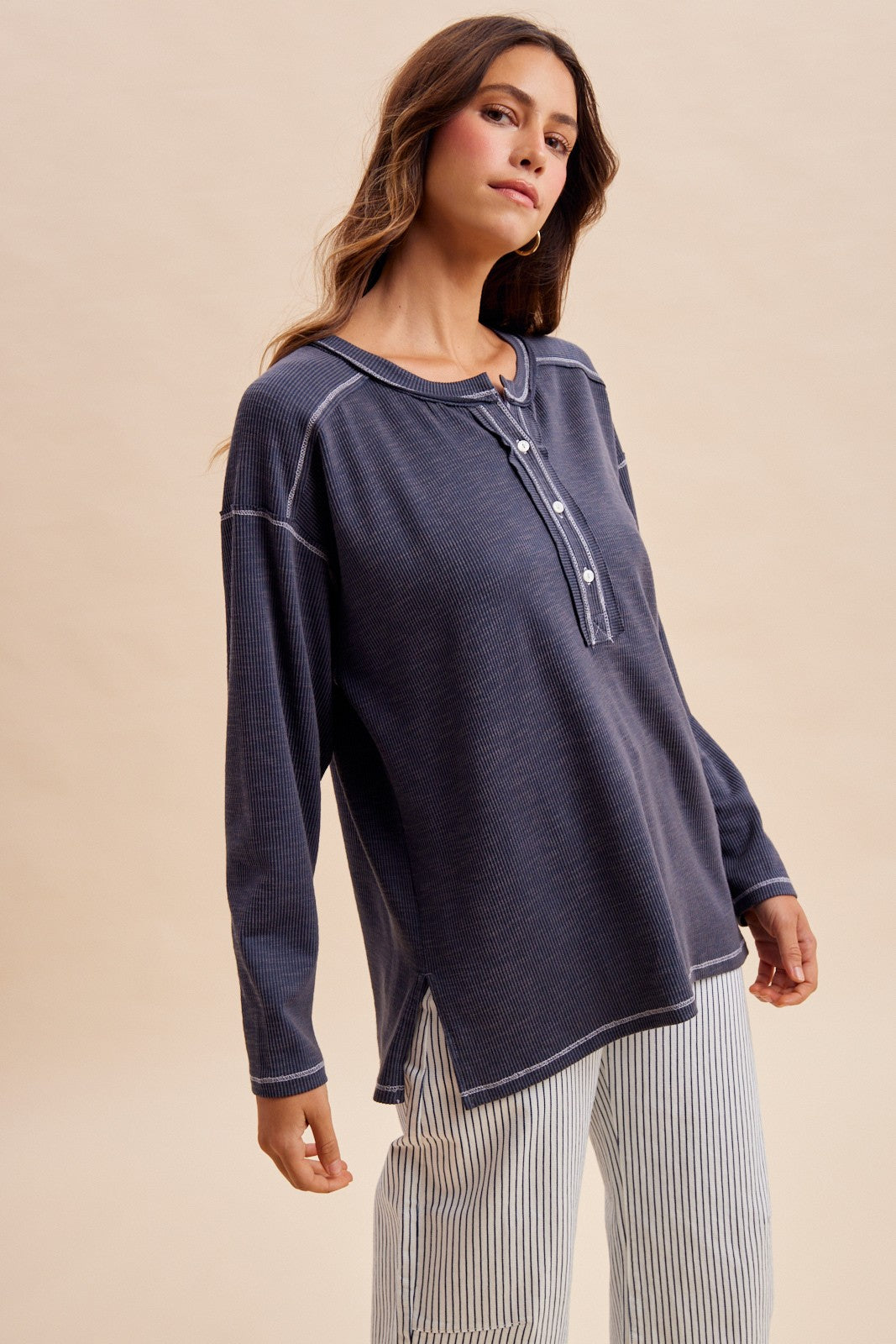 woman wearing a navy blue long sleeve henley top with button details and a relaxed fit