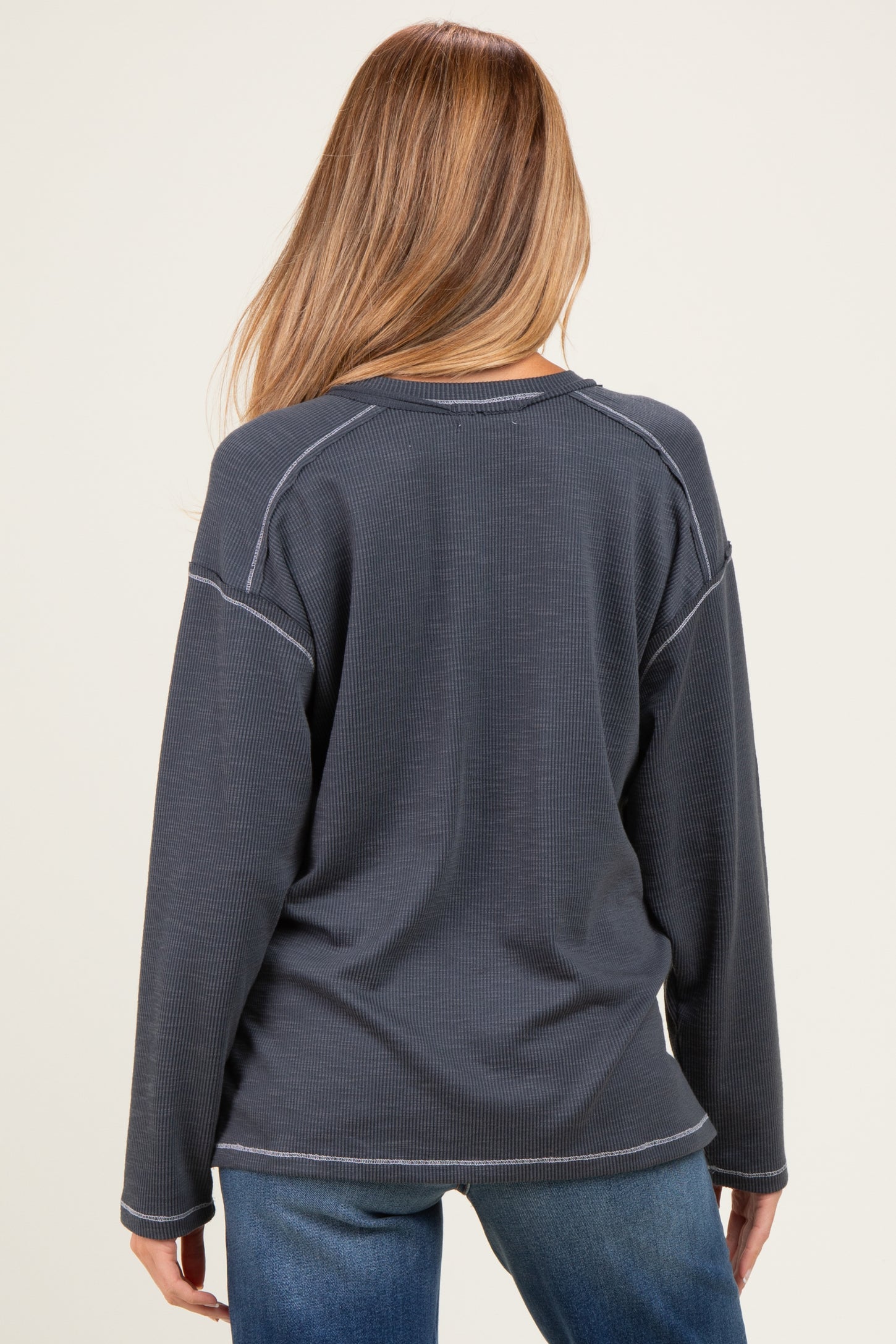 woman wearing a navy blue long sleeve maternity top with a textured finish, seen from the back