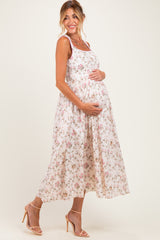 woman wearing a white floral maternity maxi dress and holding her baby bump