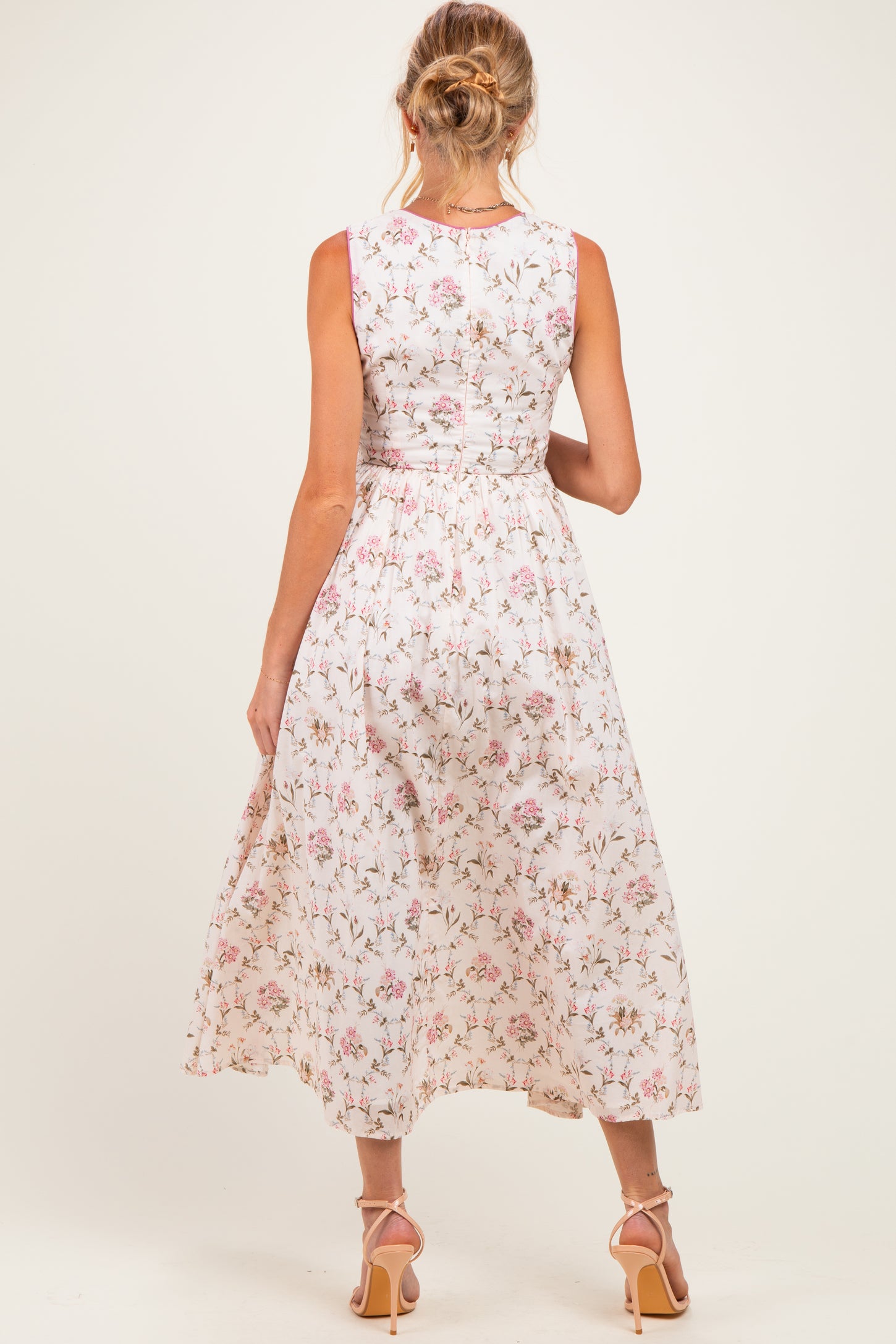 woman wearing a white floral print maternity dress with a fitted bodice and flowy skirt, showing the back view