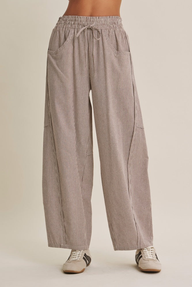 woman wearing striped wide-leg trousers with an elastic waistband and side pockets, paired with casual sneakers