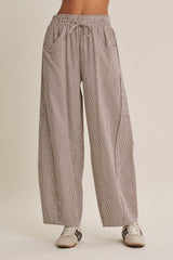 woman wearing striped wide-leg trousers with an elastic waistband and side pockets, paired with casual sneakers