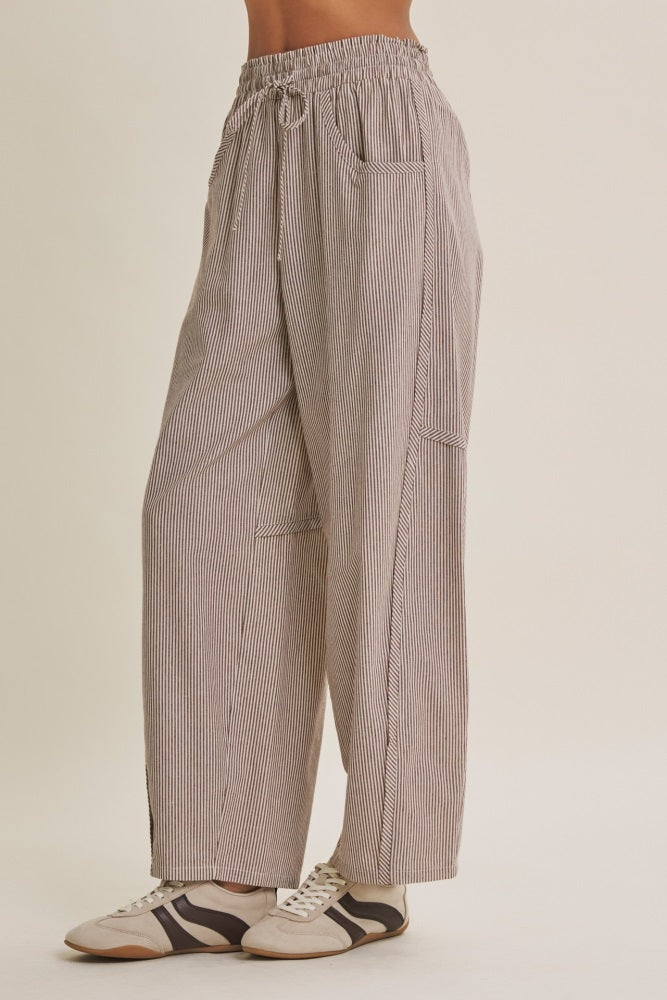 woman wearing beige and white striped wide-leg pants with side pockets and an elastic waistband, paired with sneakers
