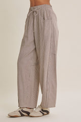 woman wearing beige and white striped wide-leg pants with side pockets and an elastic waistband, paired with sneakers