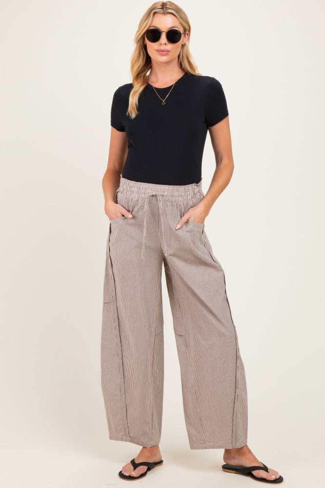 woman wearing a black short sleeve maternity top and relaxed striped maternity pants with pockets
