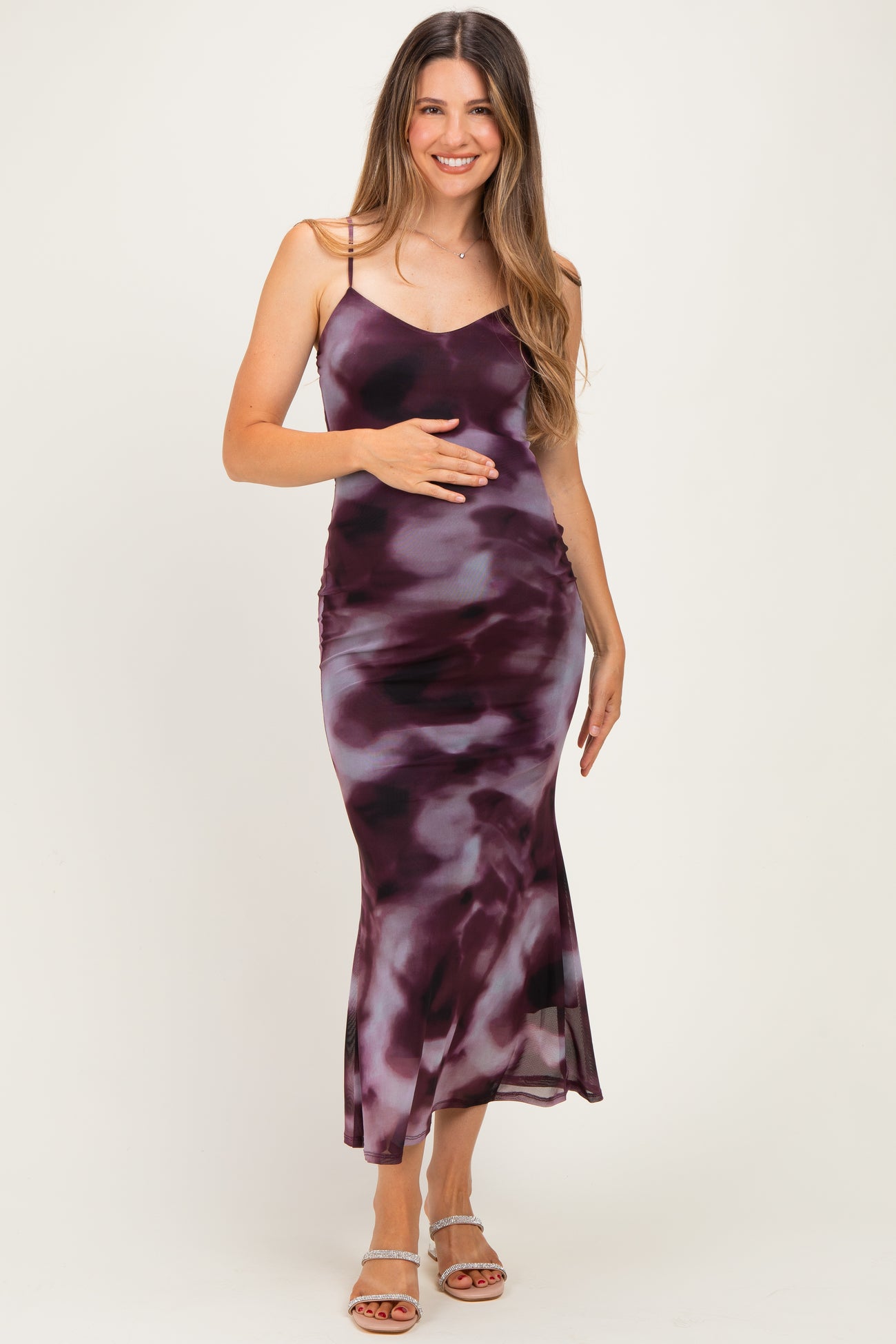 woman wearing a purple and pink tie-dye maternity dress and holding her baby bump