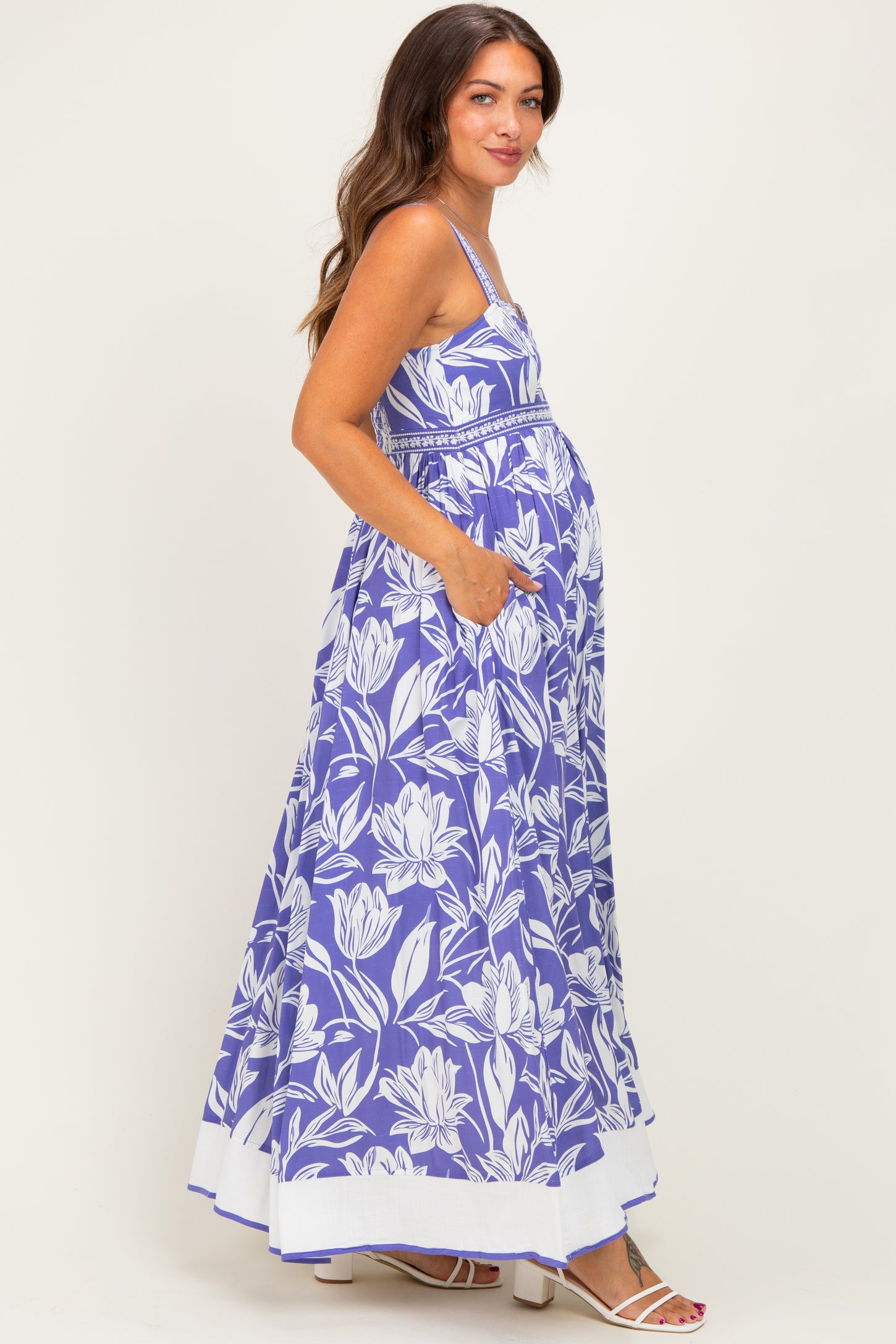 woman wearing a purple floral maternity maxi dress with pockets and a visible baby bump
