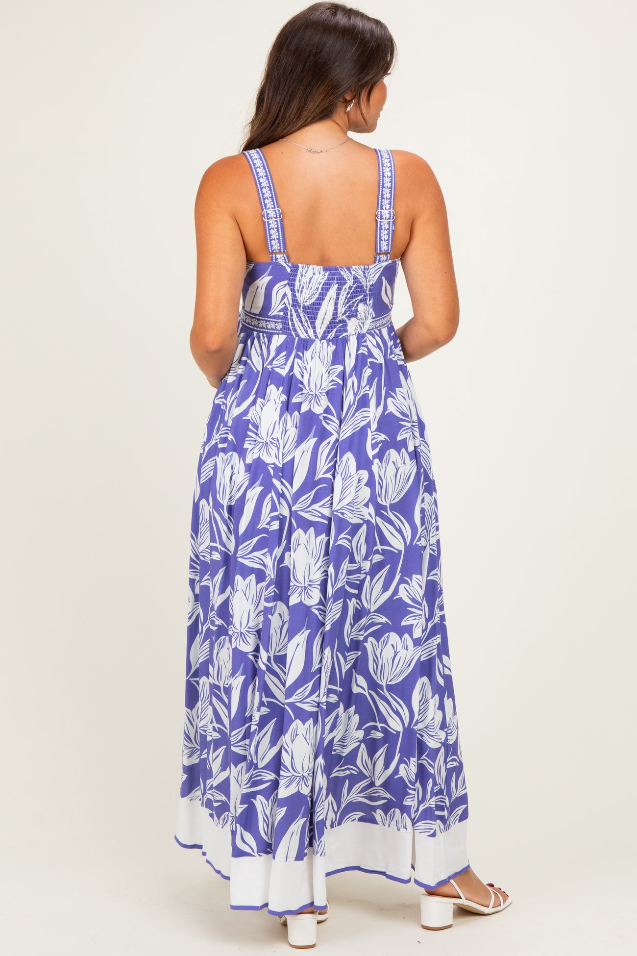 woman wearing a purple floral maternity maxi dress with adjustable straps and a fitted bodice