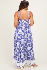 woman wearing a purple floral maternity maxi dress with adjustable straps and a fitted bodice