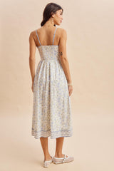 woman wearing a light blue floral midi dress with a smocked bodice and adjustable straps, showing the back view