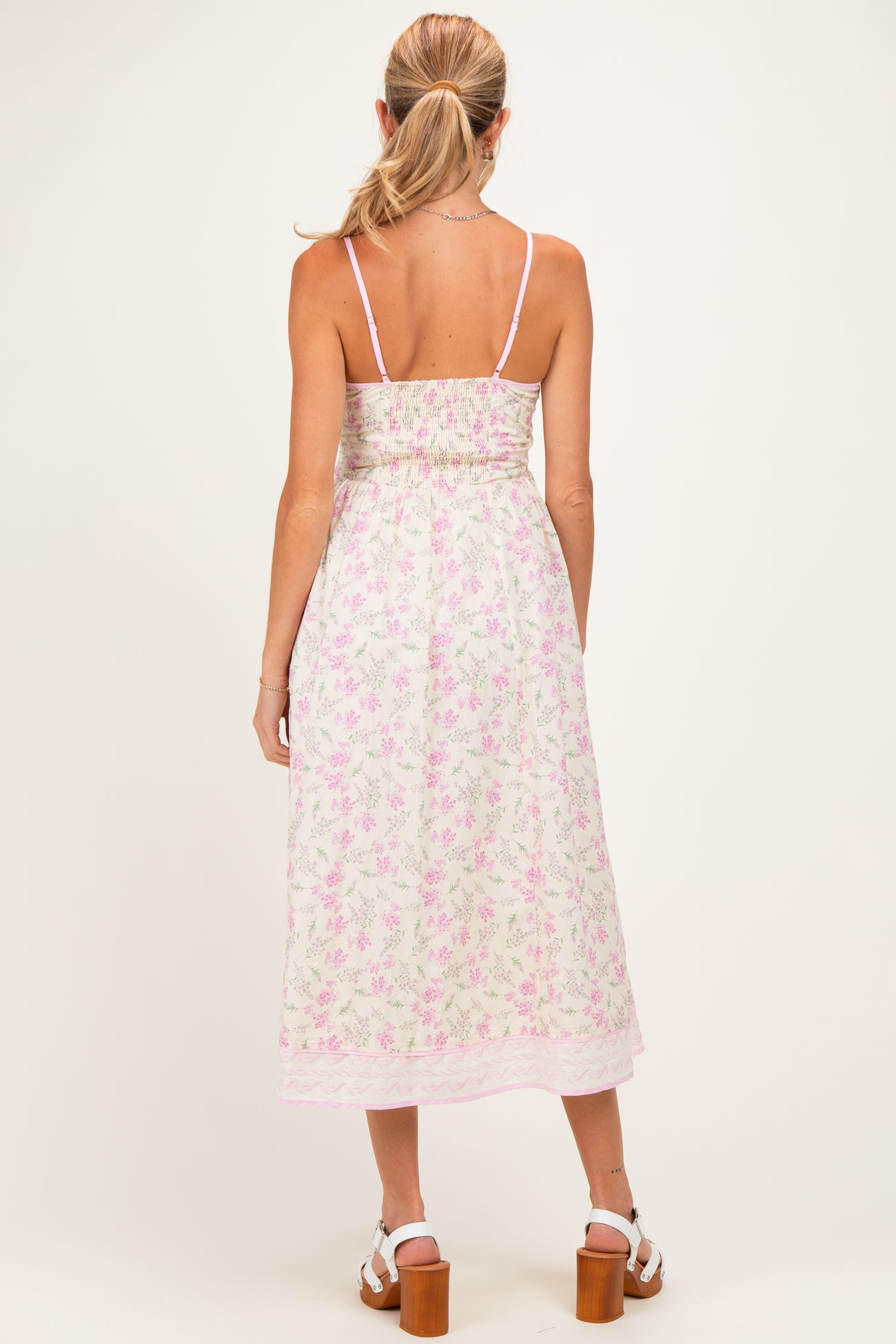 woman wearing a floral maternity dress with adjustable straps and a smocked back, showcasing a relaxed fit