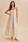 woman wearing a cream floral maxi dress with a tiered hem and a bow detail on one shoulder