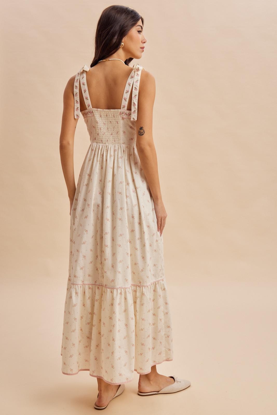 woman wearing a back view of a cream floral maxi dress with ruffled straps and tiered skirt