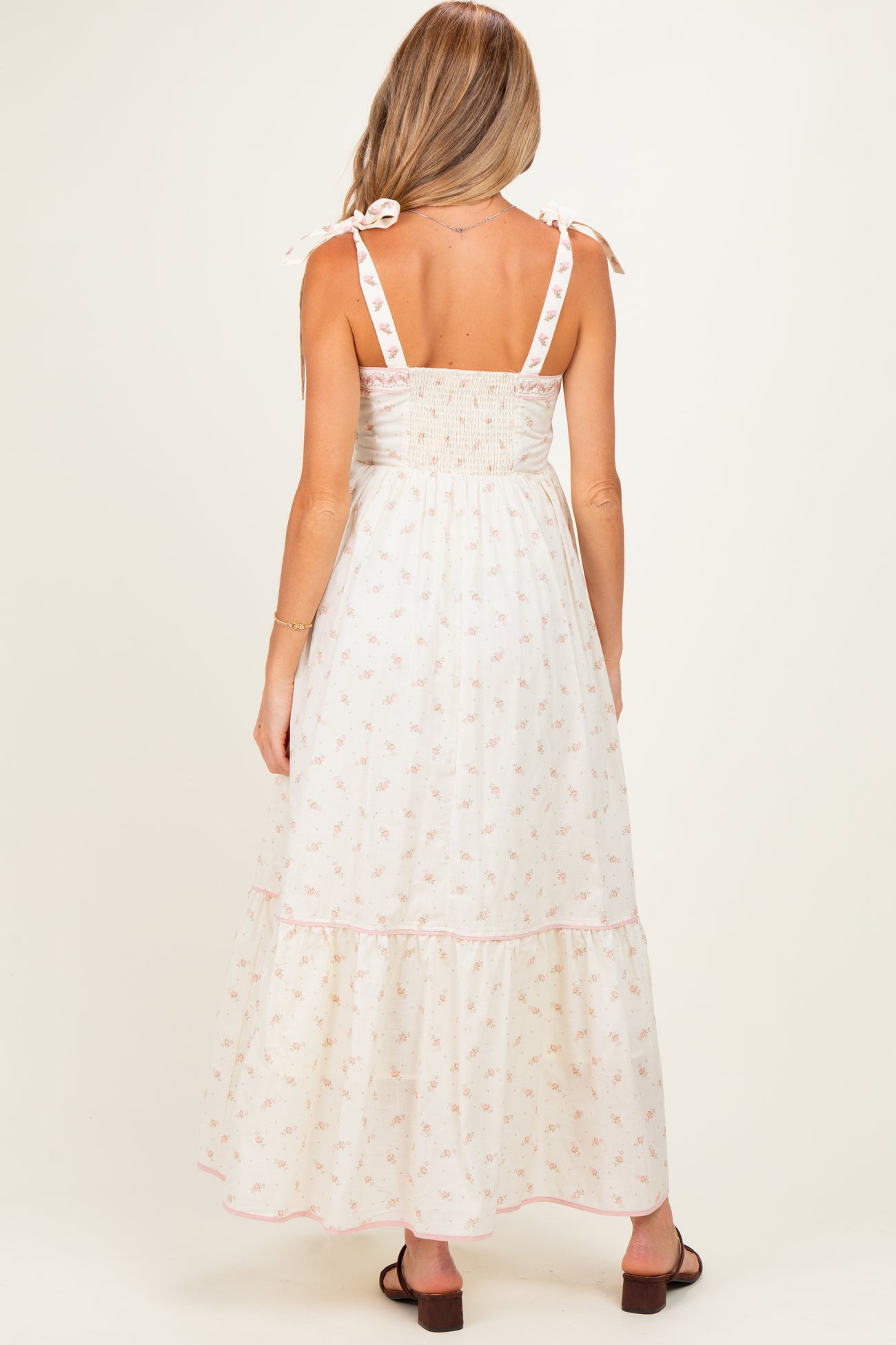woman wearing a floral print maternity maxi dress with a smocked back and tie straps