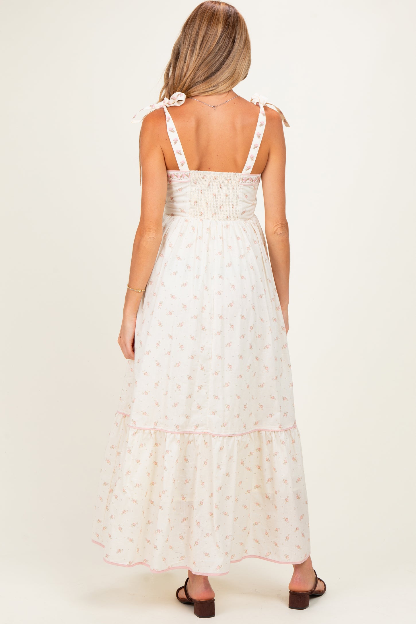 woman wearing a floral print maternity maxi dress with a smocked back and tie straps