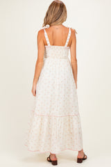 woman wearing a floral print maternity maxi dress with a smocked back and tie straps