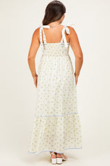 woman wearing a white floral print maternity maxi dress with tie straps, showcasing a smocked bodice and tiered skirt